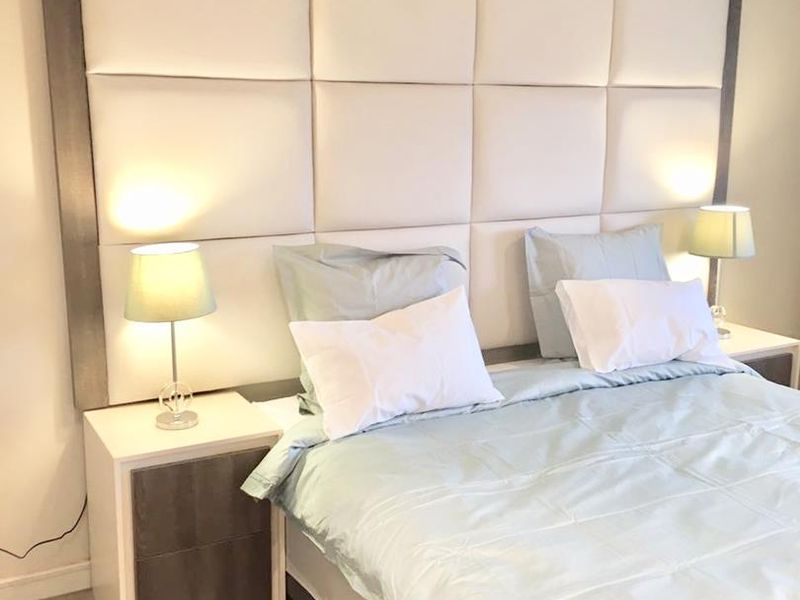 A well-maintained bedroom featuring a large, modern upholstered headboard as the central focal point.