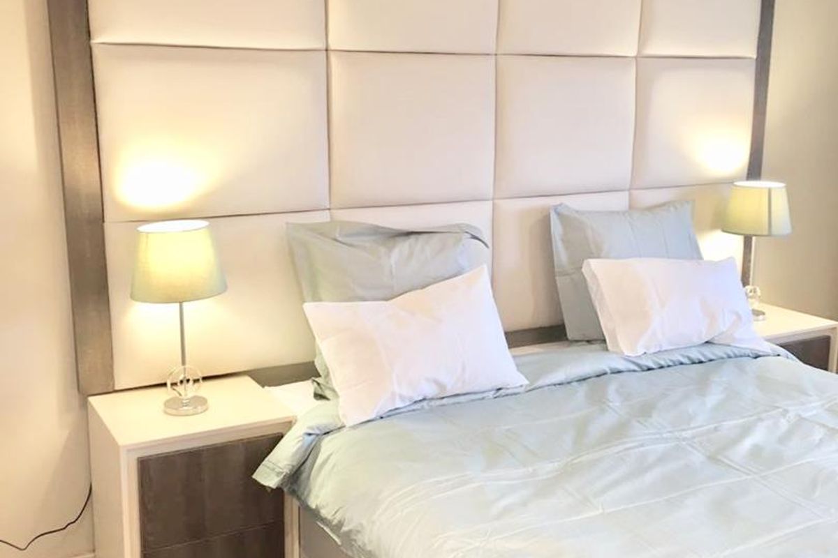 A well-maintained bedroom featuring a large, modern upholstered headboard as the central focal point.