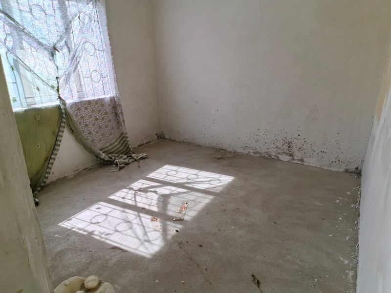 An empty bedroom featuring unfinished concrete flooring and walls requiring cosmetic repair and painting.