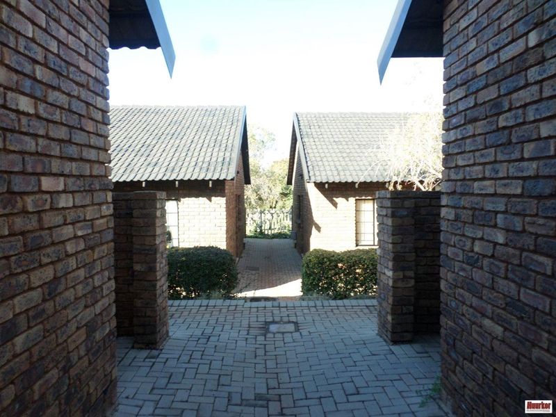 A view of the exterior rear area featuring face brick buildings with tiled roofs and a paved walkway between the units.