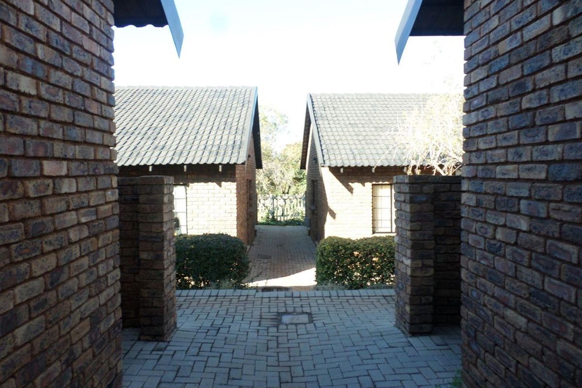 A view of the exterior rear area featuring face brick buildings with tiled roofs and a paved walkway between the units.