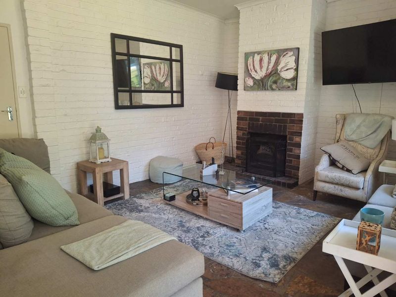 Cozy living room featuring a traditional brick fireplace, rustic stone flooring, and painted brick walls, creating a warm and inviting atmosphere.
