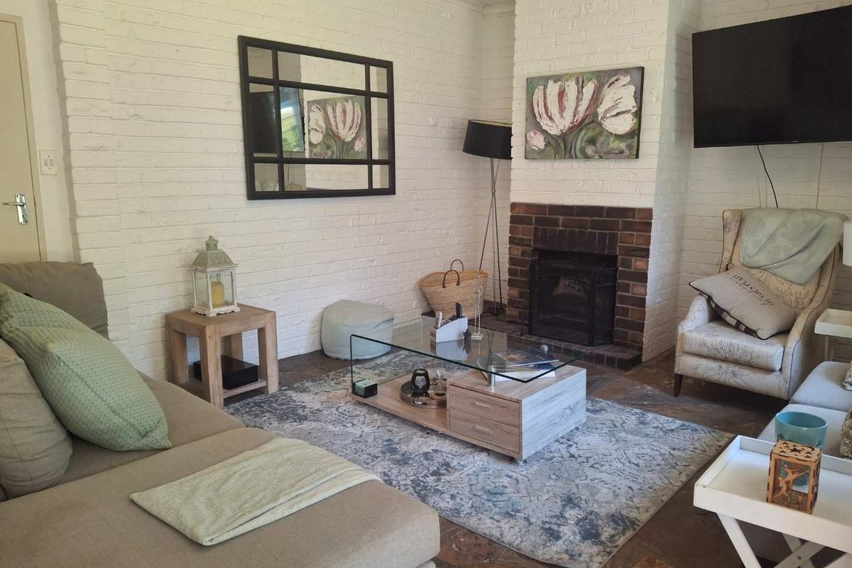 Cozy living room featuring a traditional brick fireplace, rustic stone flooring, and painted brick walls, creating a warm and inviting atmosphere.