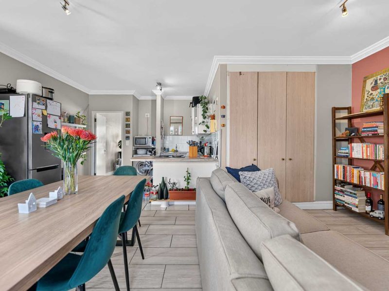 Open-plan living and dining area featuring tiled floors, neutral walls, and a functional kitchen space with built-in cabinetry and storage.