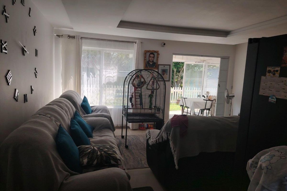 A living room featuring tiled flooring, a recessed ceiling, and a sliding glass door providing access to an outdoor patio area.