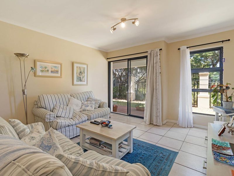 A bright living room featuring tiled flooring, track lighting, and a sliding glass door providing direct access to the outdoor patio area.