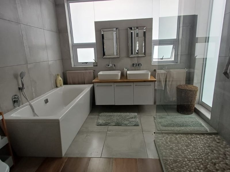 Modern bathroom featuring a double vanity with vessel sinks, a freestanding bathtub, and a spacious walk-in shower with a pebble floor finish.