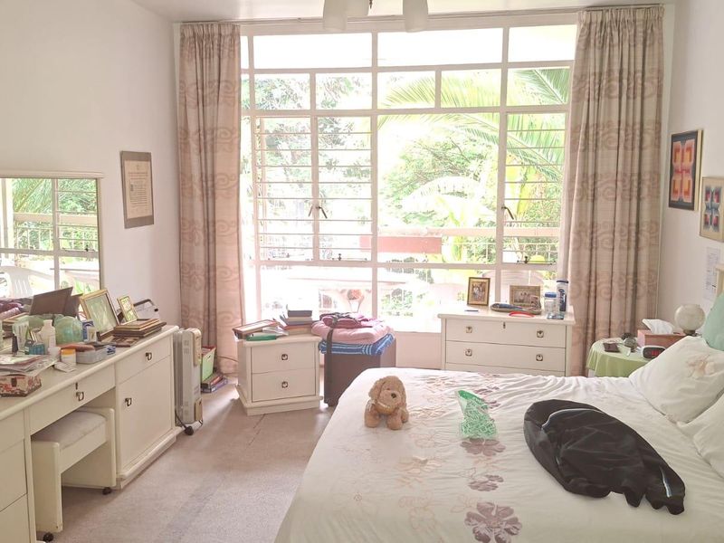 A spacious bedroom featuring a large window that allows for ample natural light, complete with built-in vanity cabinetry and carpeted flooring.