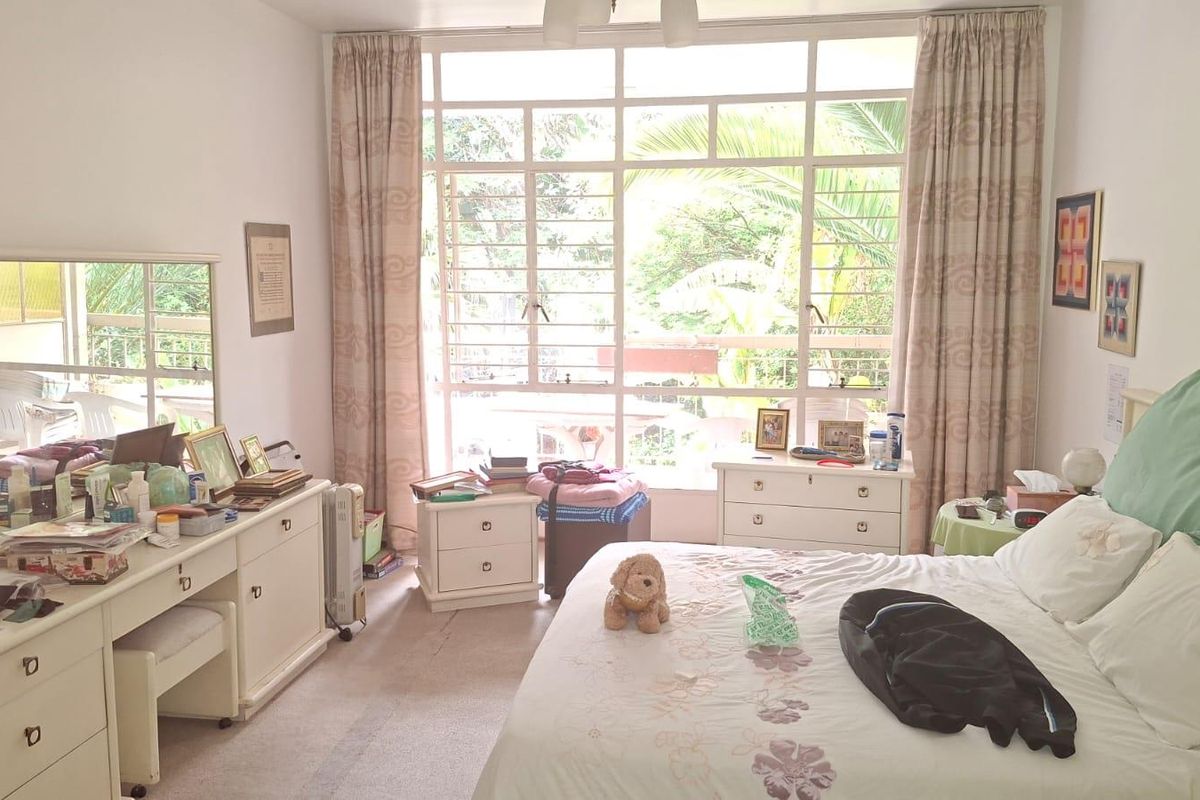 A spacious bedroom featuring a large window that allows for ample natural light, complete with built-in vanity cabinetry and carpeted flooring.