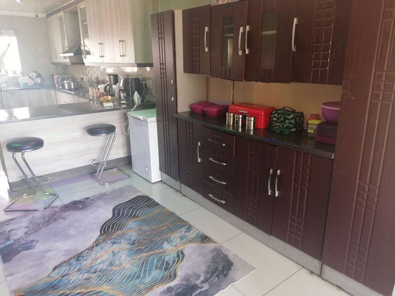 A functional kitchen featuring dark wood cabinetry, granite countertops, and a breakfast bar area with tiled flooring.