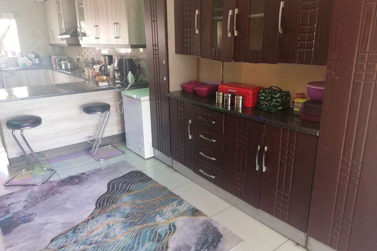 A functional kitchen featuring dark wood cabinetry, granite countertops, and a breakfast bar area with tiled flooring.