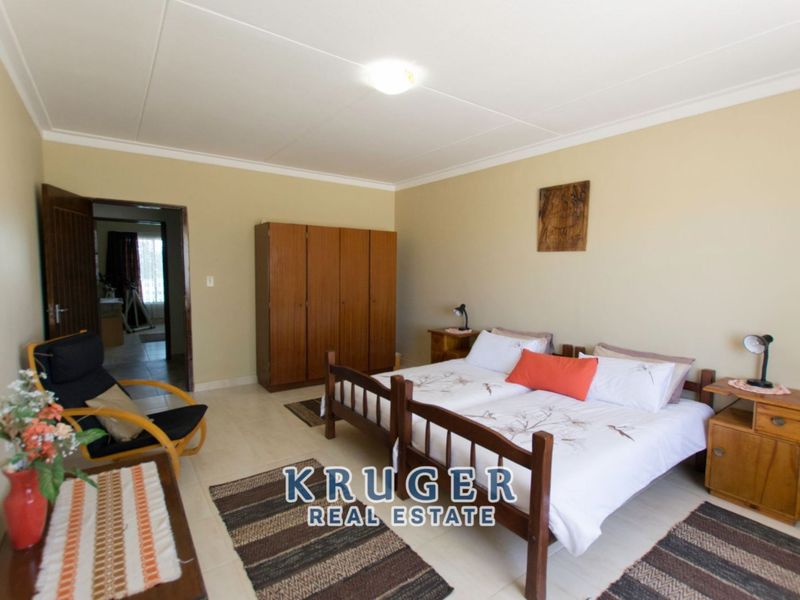 A spacious bedroom featuring tiled flooring, neutral wall finishes, and built-in wooden cabinetry, providing a functional and comfortable living space.