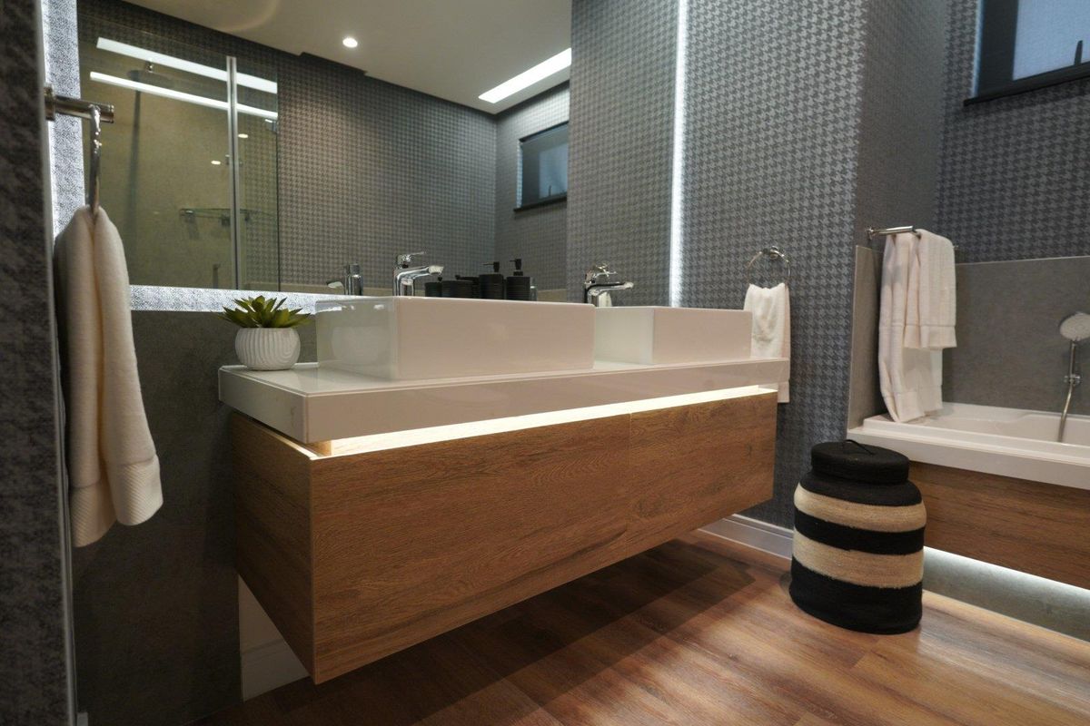 Modern bathroom featuring a floating double vanity with integrated lighting, vessel sinks, a glass-enclosed shower, and a built-in bathtub with contemporary finishes.