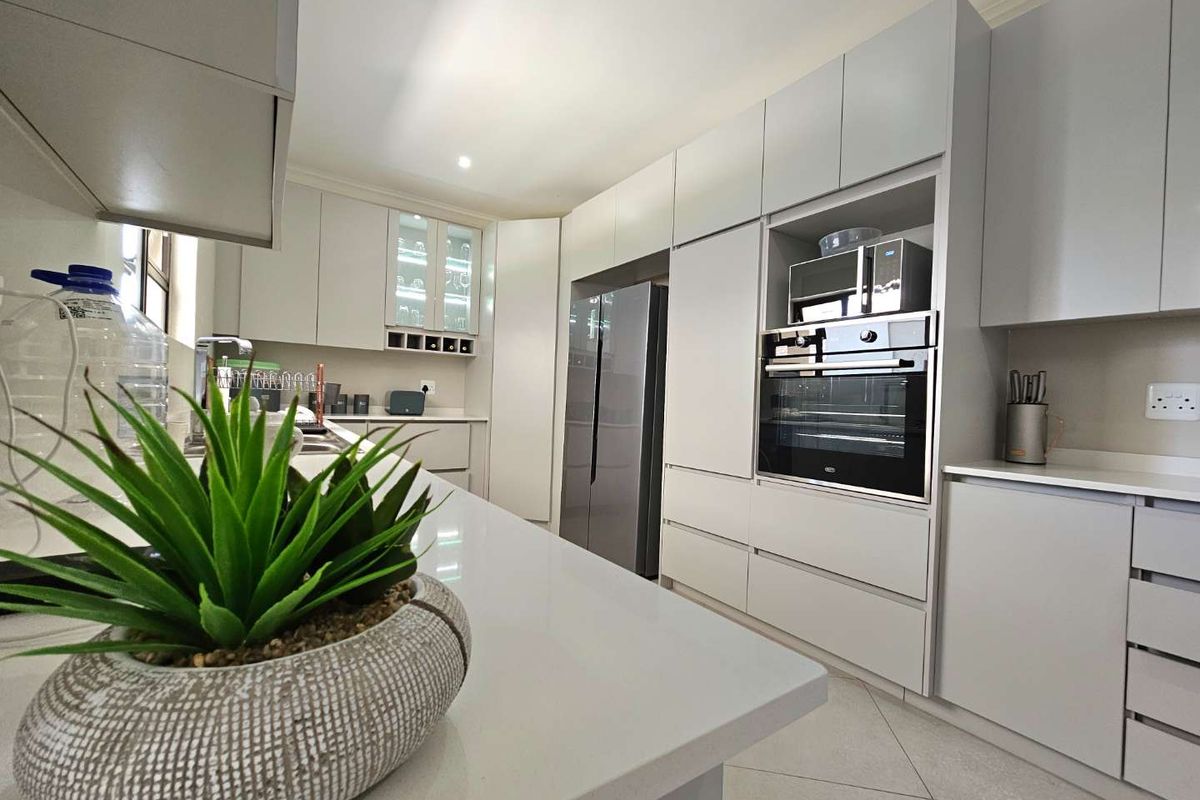 Modern kitchen featuring sleek cabinetry, stone countertops, integrated oven, built-in microwave, and a central island, offering a clean and functional culinary space.