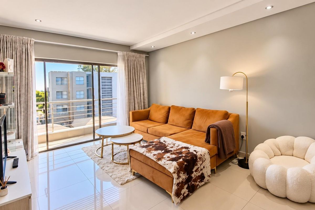 A bright and modern living room featuring large sliding glass doors that open onto a balcony, complemented by polished tiled flooring and recessed ceiling lighting.