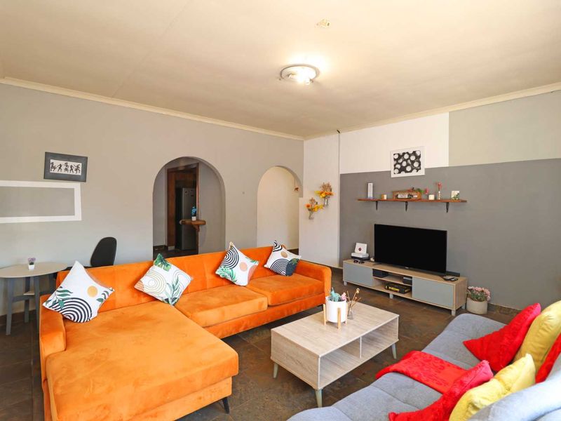 A spacious living room featuring tiled flooring, distinctive arched doorways leading to adjacent areas, and neutral wall finishes with decorative accent painting.