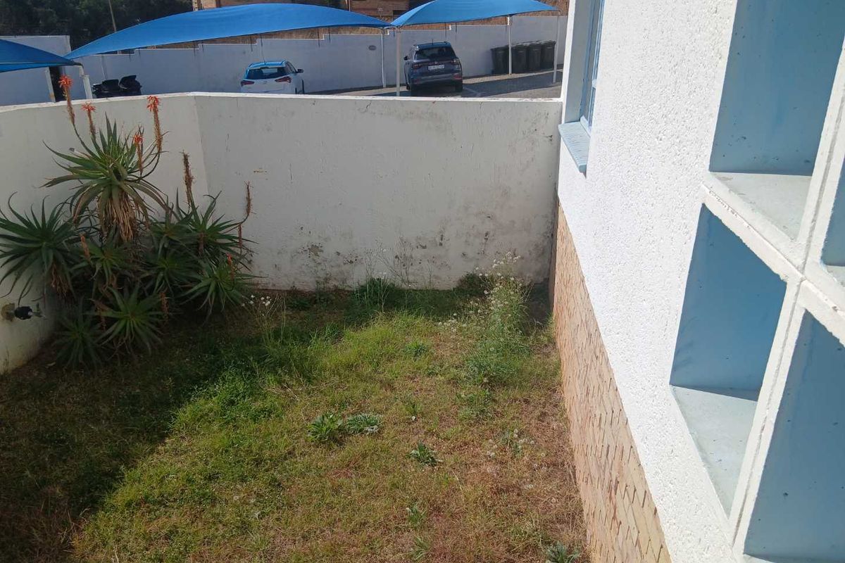 A small rear garden area featuring a boundary wall and brick exterior finish, currently requiring landscaping and maintenance.