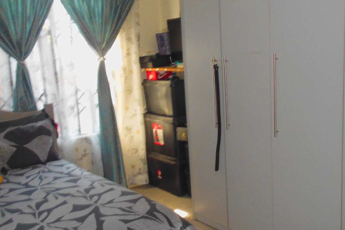 A bedroom featuring built-in wardrobes and tiled flooring, offering functional storage space.