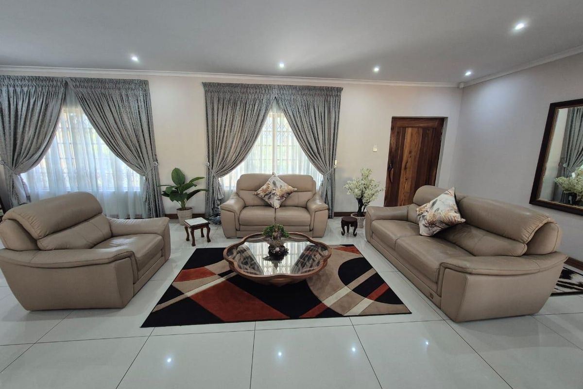 Spacious living room featuring large windows with curtain rails, recessed downlighting, and polished tiled flooring.