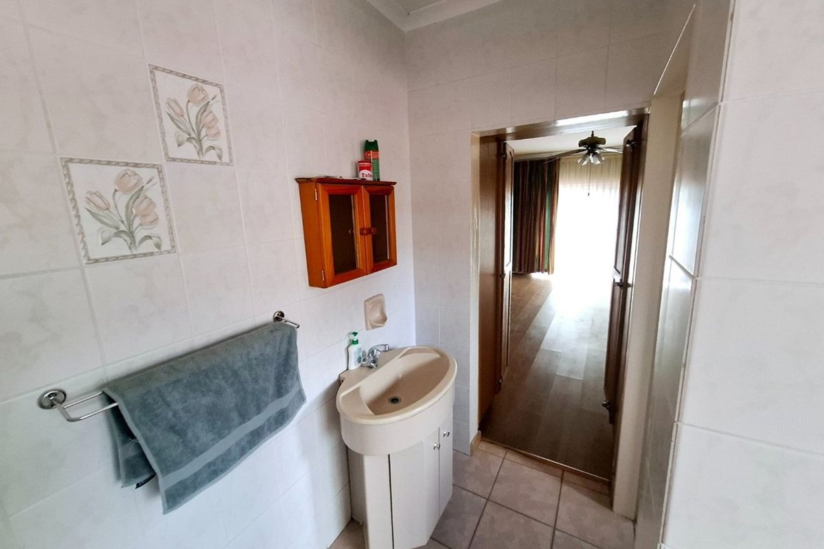 A functional bathroom featuring tiled walls, a pedestal basin, and a towel rail, with direct access to an adjacent living area.