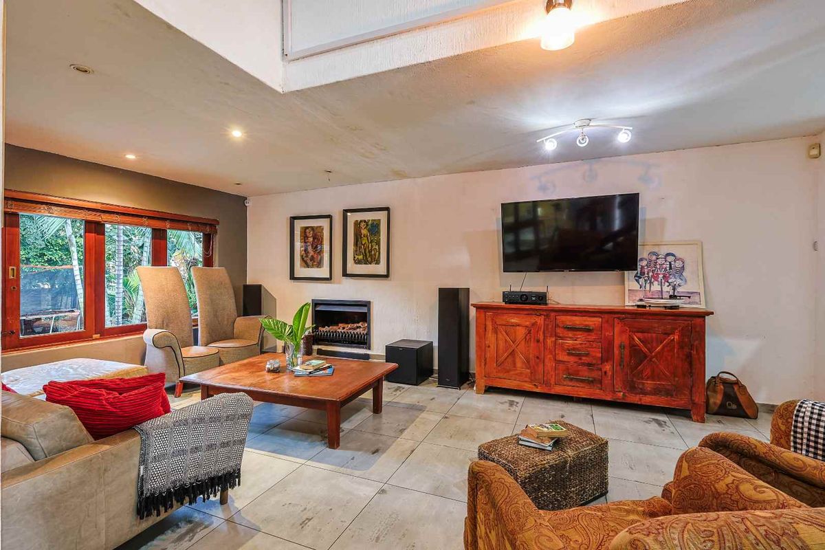 Spacious living room featuring tiled flooring, a built-in fireplace, and large timber-framed windows, offering a comfortable and functional living space.