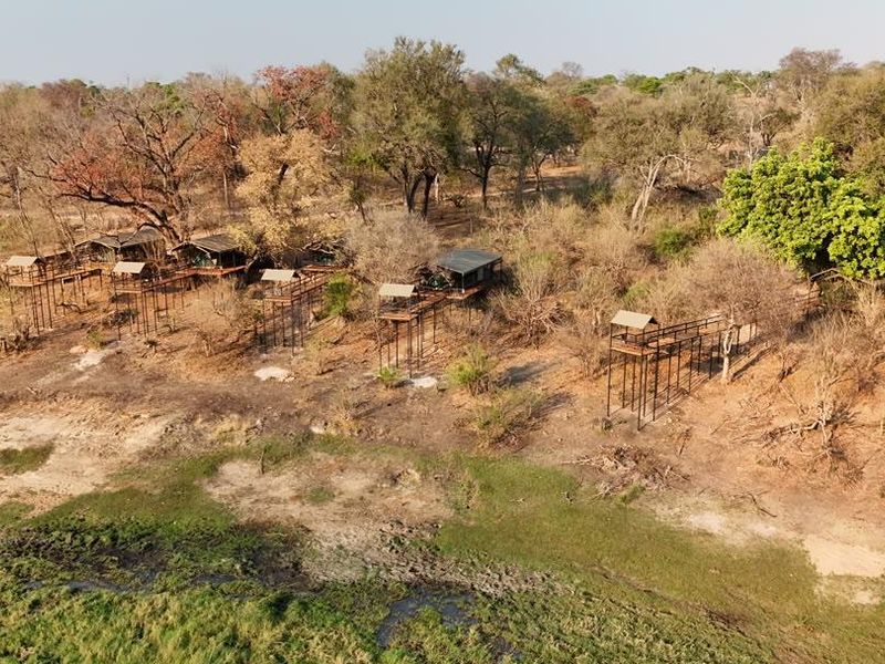 Aerial view of a lodge property featuring multiple elevated structures and timber walkways set within a natural bushveld landscape along a riverbank.