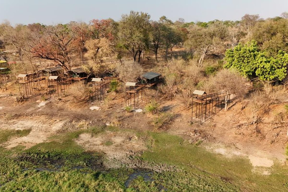 Aerial view of a lodge property featuring multiple elevated structures and timber walkways set within a natural bushveld landscape along a riverbank.