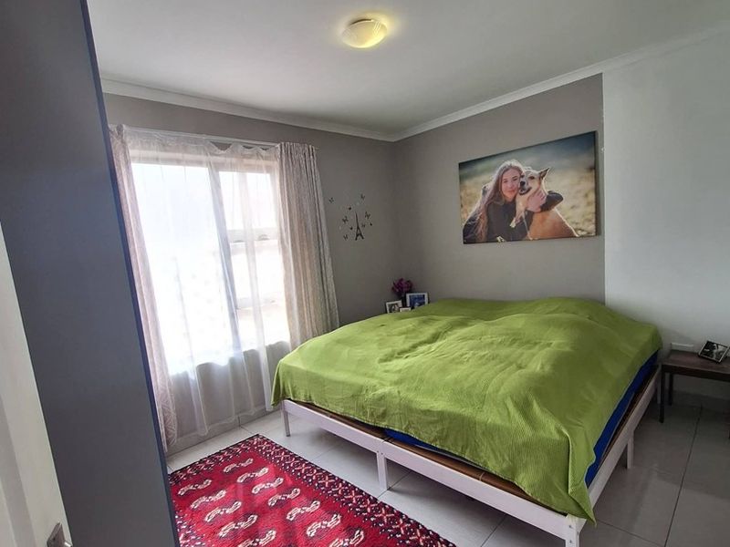 A functional bedroom featuring tiled flooring, a central ceiling light, and a window allowing natural light into the space.