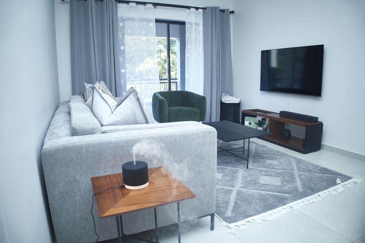 A well-maintained living room featuring neutral tiled flooring and a sliding glass door providing access to an outdoor balcony area.