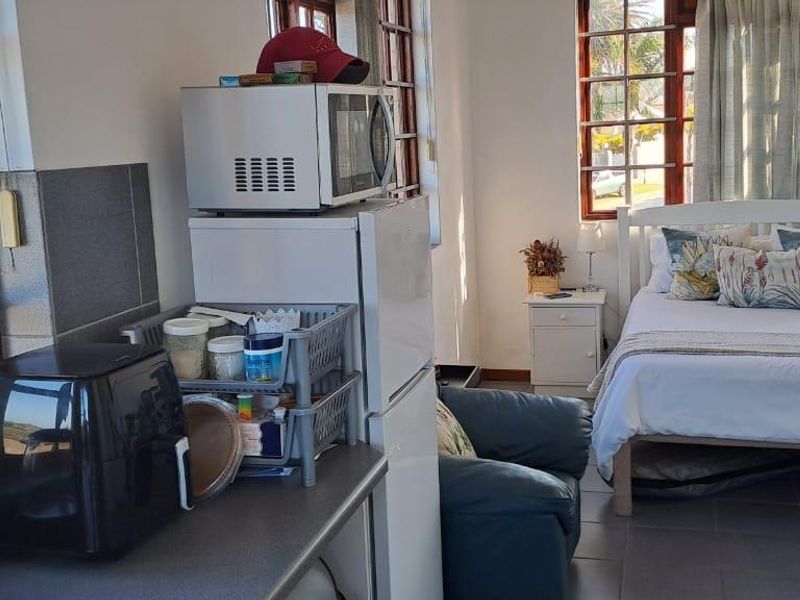 A bedroom featuring tiled flooring and timber-framed windows, providing a functional living space with integrated kitchen-style storage area.