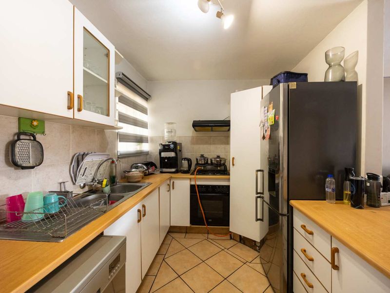 Compact kitchen featuring white cabinetry, laminate countertops, tiled backsplash, and built-in cooking appliances with a functional layout.