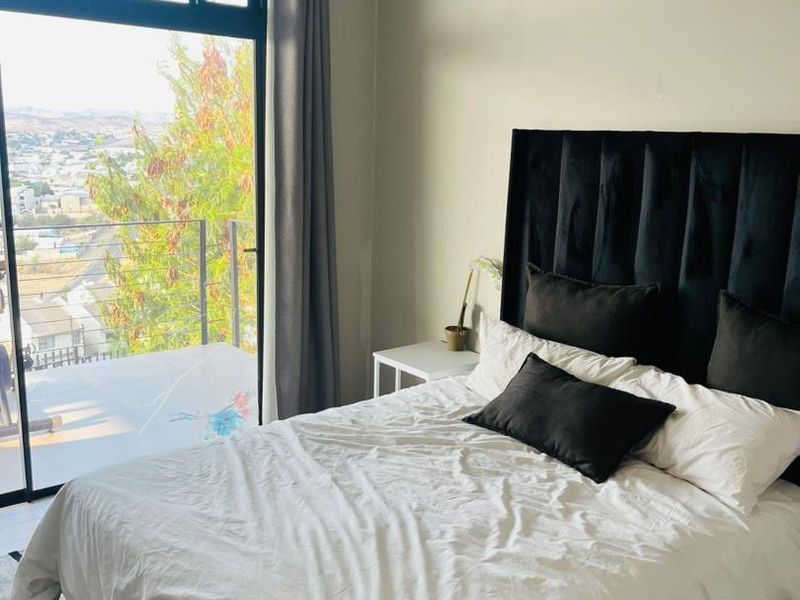 A bedroom featuring a large sliding glass door with balcony access, providing natural light and scenic views.