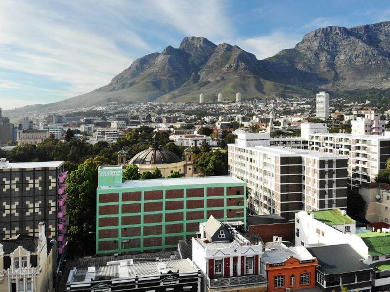 An elevated aerial view of the urban cityscape featuring Table Mountain in the background.