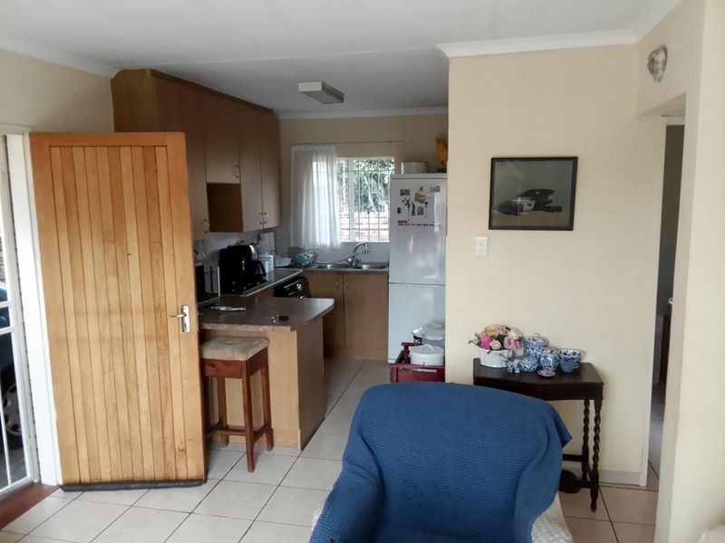 A functional kitchen featuring built-in wooden cabinetry, laminate countertops, a breakfast bar, and tiled flooring, providing a practical layout for daily meal preparation.