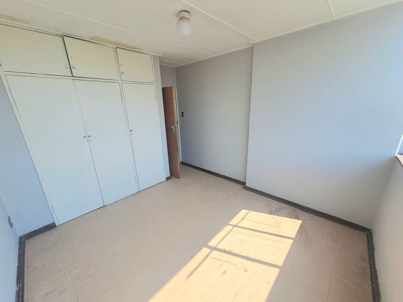 An empty bedroom featuring built-in cupboards and tiled flooring, offering a blank canvas for renovation and interior design updates.