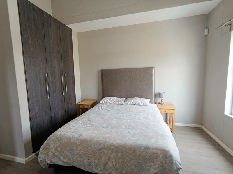 A well-maintained bedroom featuring modern laminate flooring and floor-to-ceiling built-in cupboards, providing ample storage space.
