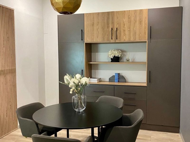 Modern dining area featuring custom built-in cabinetry with wood and grey finishes, recessed lighting, and elegant slatted wood wall detailing.