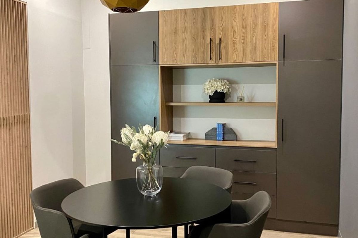 Modern dining area featuring custom built-in cabinetry with wood and grey finishes, recessed lighting, and elegant slatted wood wall detailing.