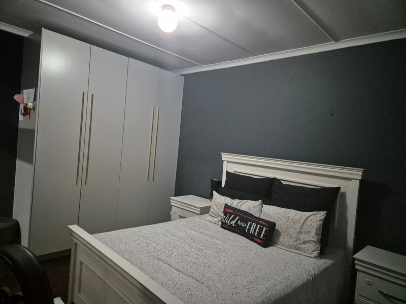 A well-maintained bedroom featuring dark accent walls and ample built-in cupboard storage space.