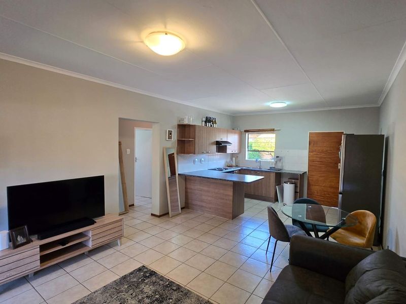 Open-plan living and kitchen area featuring tiled flooring, built-in cabinetry, and a functional layout suitable for modern living.