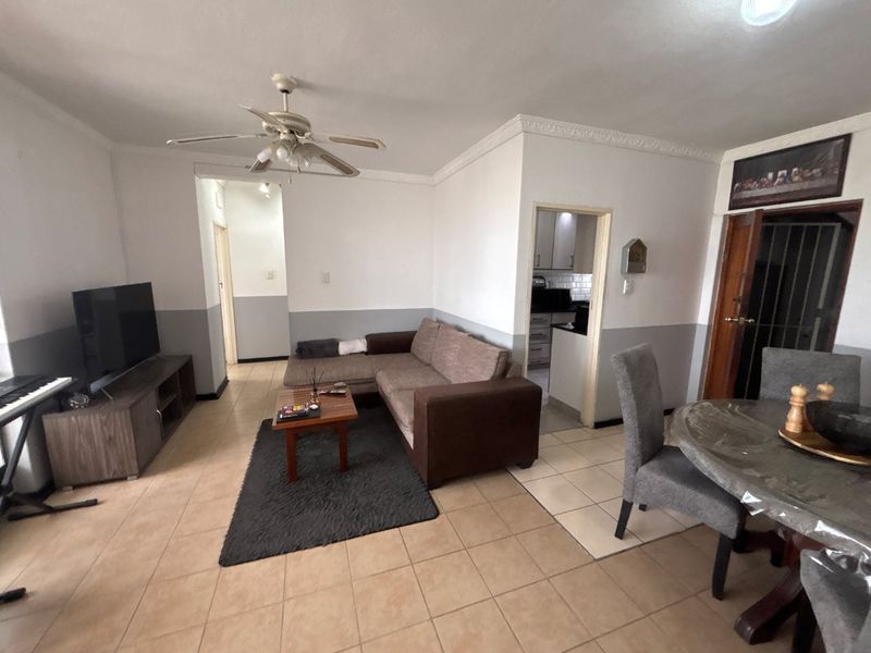 Open plan living and dining area featuring tiled flooring, crown molding, and a ceiling fan, with direct access to the kitchen.