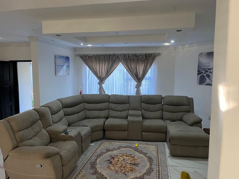 A spacious living room featuring a recessed ceiling with downlights, decorative coving, and tiled flooring, offering a comfortable and well-lit area.