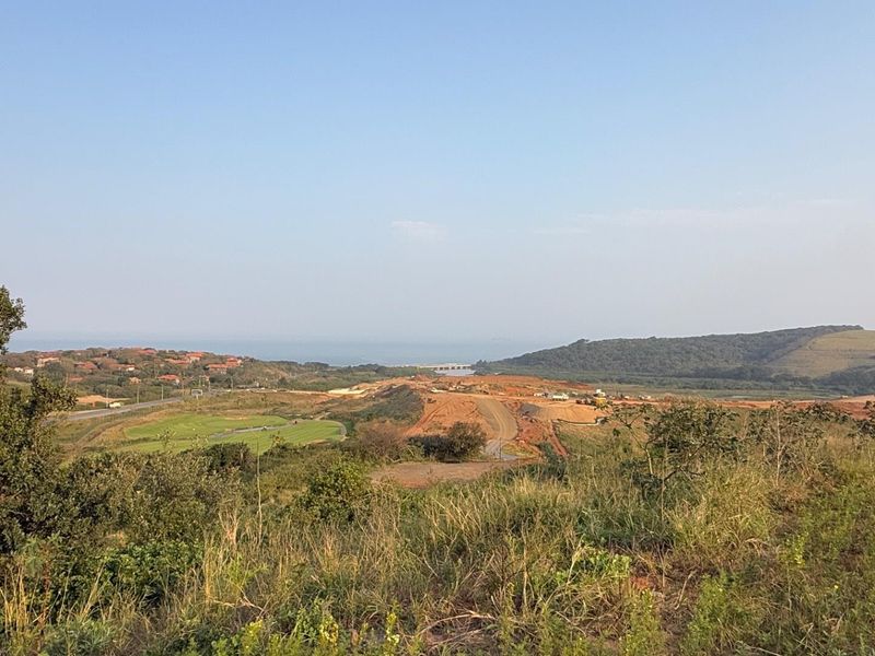 A wide-angle view of the surrounding landscape, featuring rolling hills, coastal terrain, and distant residential development.