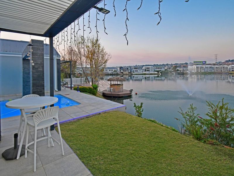 Covered patio area featuring a swimming pool, stone-clad feature wall, and direct views over the lake and surrounding estate.
