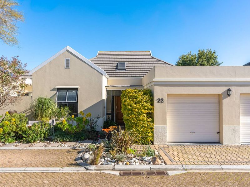 Front elevation of a well-maintained house featuring a paved driveway, single garage, and landscaped garden area.