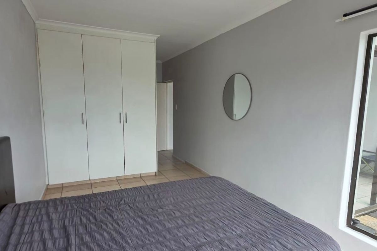 A bedroom featuring built-in cupboards, tiled flooring, and a sliding glass door providing access to an outdoor area.