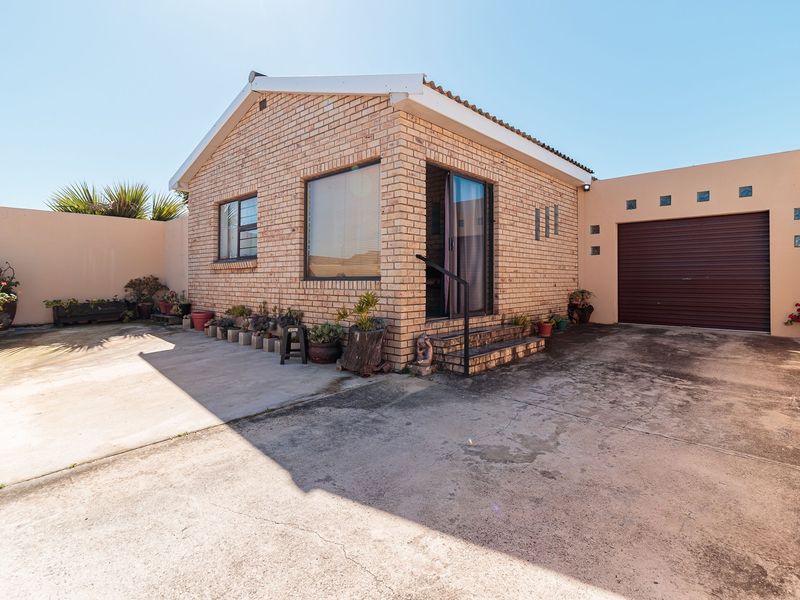 Front exterior view of a face brick house featuring a concrete driveway, single garage with a roller shutter door, and surrounding boundary walls.