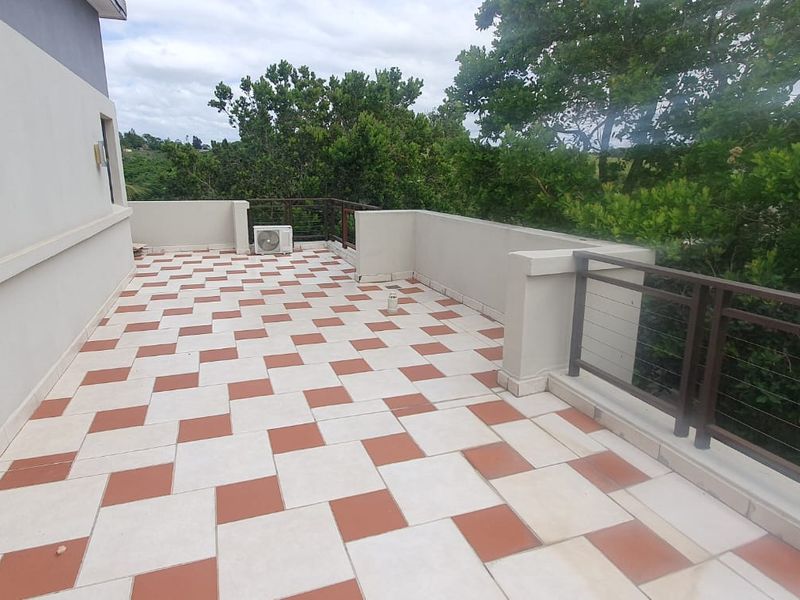 A spacious balcony featuring patterned tiled flooring and metal railings, offering an open outdoor area suitable for relaxation.