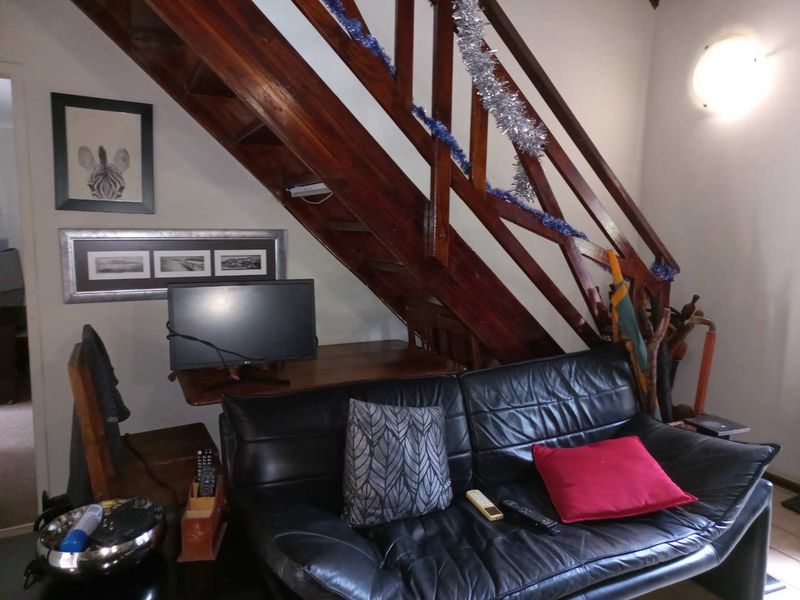 A living room area featuring a wooden staircase with a built-in balustrade and a wall-mounted light fixture.