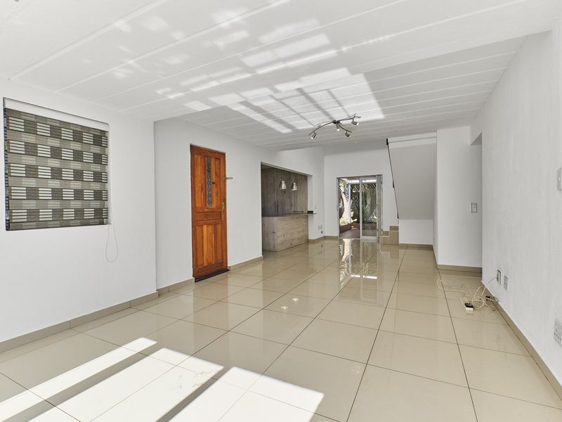 Spacious open-plan living area featuring polished tile flooring, a built-in bar, and direct access to the rear patio through sliding glass doors.